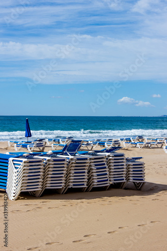 empty deck chairs by the sea  background with sea waves  sand and blue sky