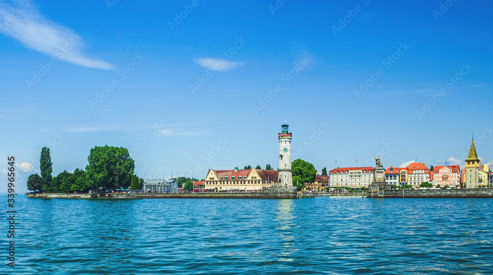 View of the Lindau embankment from the lake. The New lighthouse, the Bavarian lion and the Mangturm tower. lake Constance. Germany. Soft focus, blurry background.