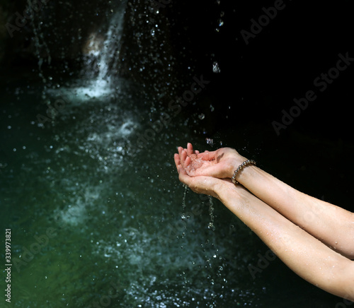 Pure mountain river water in the hands of a woman, dripping from above. Women's hands with water splashes