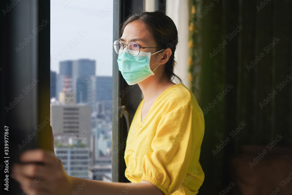Young asian woman in medical mask at home for self quarantine. She is bored because stay at home campaign for coronavirus prevention. Concept prevention COVID-19, Coronavirus outbreak situation
