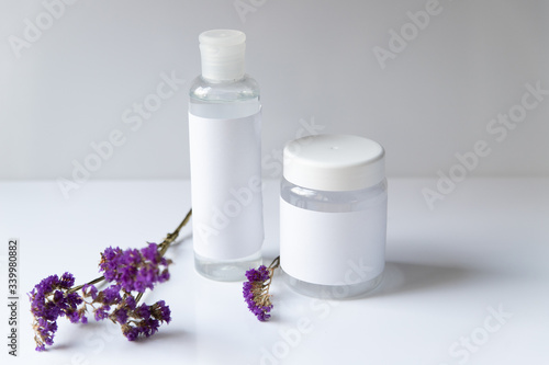 Cosmetic bottle for liquid, cream, gel, lotion. Hand sanitizer. Organic natural science beauty product. Battle with purple flower on white background