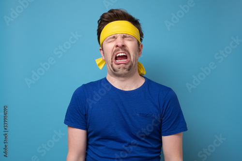 Young caucasian sport man with yellow rubber band whining and crying