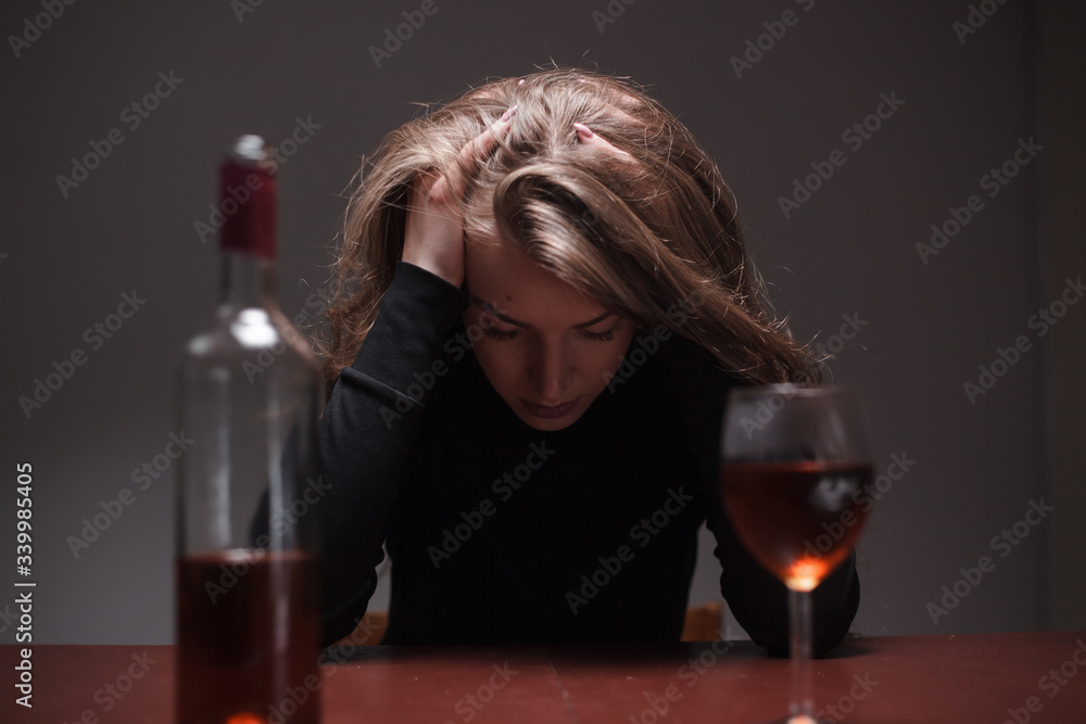 Young beautiful woman in severe depression, drinking alcohol. The concept of abuse and alcoholism. Alcoholic woman with bottle and glass of wine. Young beautiful woman in severe depression, drinking alcohol. The concept of abuse and alcoholism. Alcoholic woman with bottle and glass of wine.