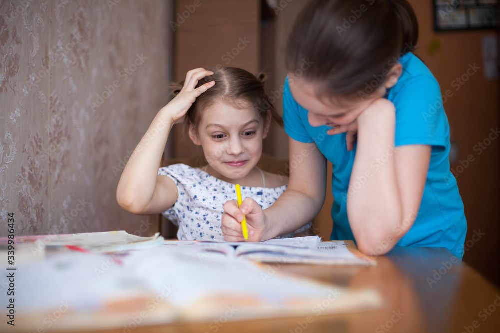 two schoolgirls at home table with lessons. two schoolgirls at home table with lessons.