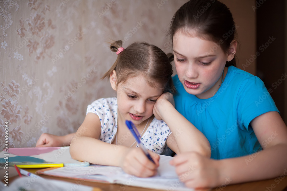two schoolgirls at home table with lessons. two schoolgirls at home table with lessons.