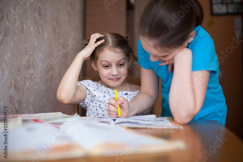  two schoolgirls at  home table with lessons.