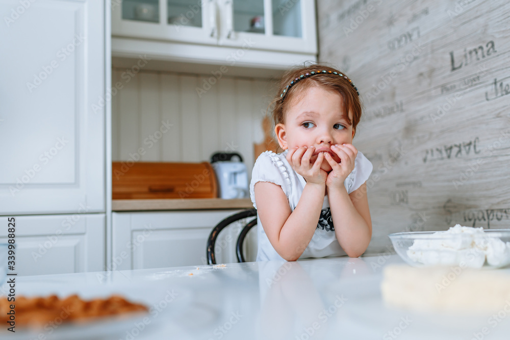 The girl in the kitchen is sitting at the table and is bored The girl in the kitchen is sitting at the table and is bored