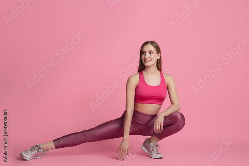 Strong, resting. Beautiful young female athlete practicing in studio, monochrome pink portrait. Sportive fit caucasian model cheerful. Body building, healthy lifestyle, beauty and action concept.