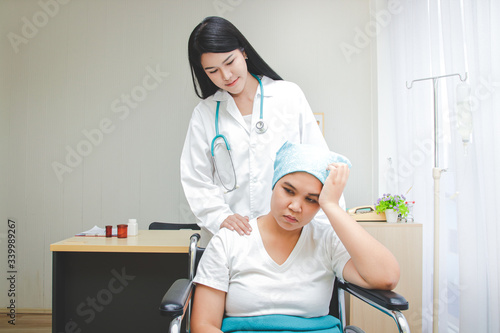 Asian female doctor provided treatment for patients sitting in a wheelchair  taking care closely. Cancer treatment hospital concept  health insurance