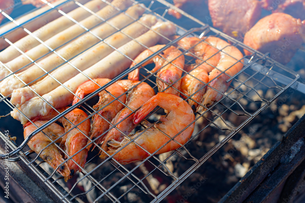 fresh juicy shish kebab sausages and prawns fried on coals on a barbecue in the backyard