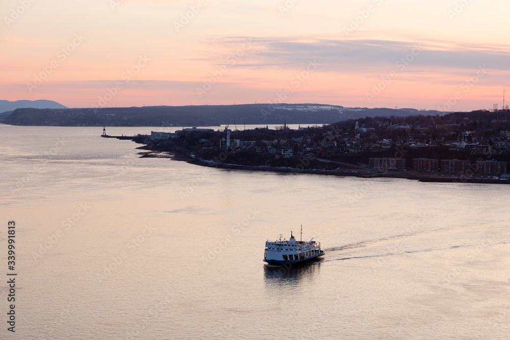 Obraz premium Aerial view of the first ferry of the day crossing the St. Lawrence River from Lévis during an early morning sunrise, Quebec City, Quebec, Canada