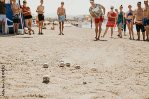 Portrait of friendly people playing petanque at leisure on the beach near a hotel full of vacationers photo