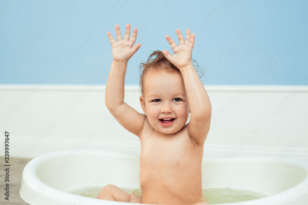 hygiene and care for young children. one year old baby bathes in the bathroom. Portrait of a cheerful laughing girl who bathes in a small bath with soapy foam hygiene and care for young children. one year old baby bathes in the bathroom. Portrait of a cheerful laughing girl who bathes in a small bath with soapy foam