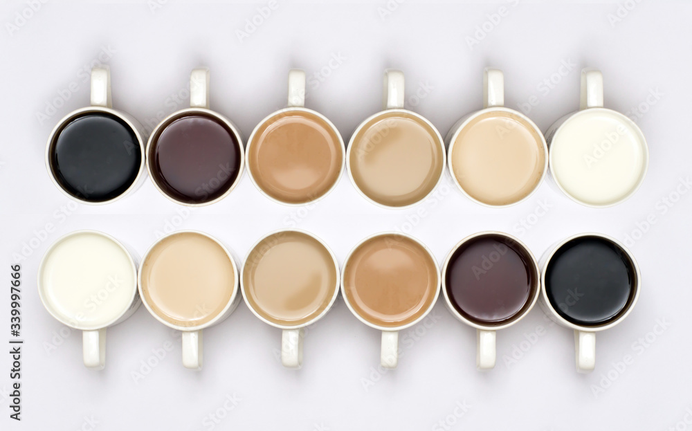 A conceptual shot with milk/tea/coffee in cups arranged in a manner which  creates a gradient effect of colours. Lighter to darker shades of drinks.  The image is on white background isolated Photos