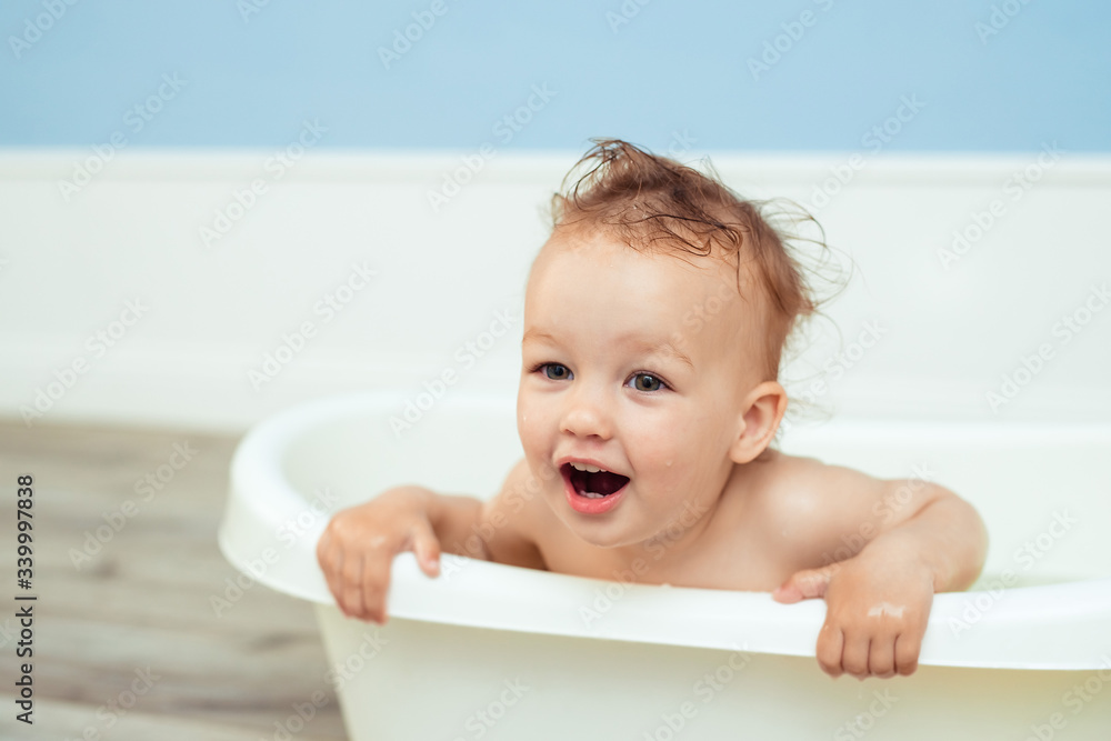 hygiene and care for young children. one year old baby bathes in the bathroom. Portrait of a cheerful laughing girl who bathes in a small bath with soapy foam hygiene and care for young children. one year old baby bathes in the bathroom. Portrait of a cheerful laughing girl who bathes in a small bath with soapy foam