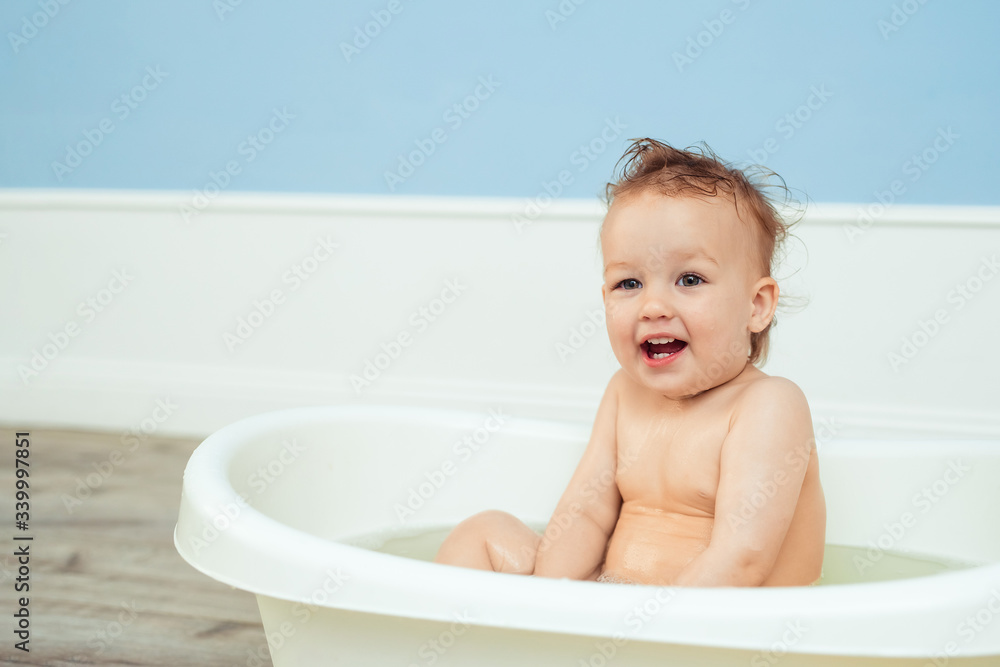 hygiene and care for young children. one year old baby bathes in the bathroom. Portrait of a cheerful laughing girl who bathes in a small bath with soapy foam hygiene and care for young children. one year old baby bathes in the bathroom. Portrait of a cheerful laughing girl who bathes in a small bath with soapy foam