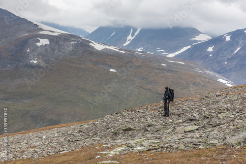 hiker witt backpack at Kungsleden trail admiring nature of Sarek