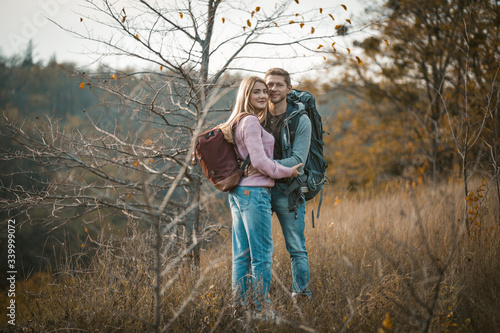 Smiling Couple With Backpacks Standing Embraced