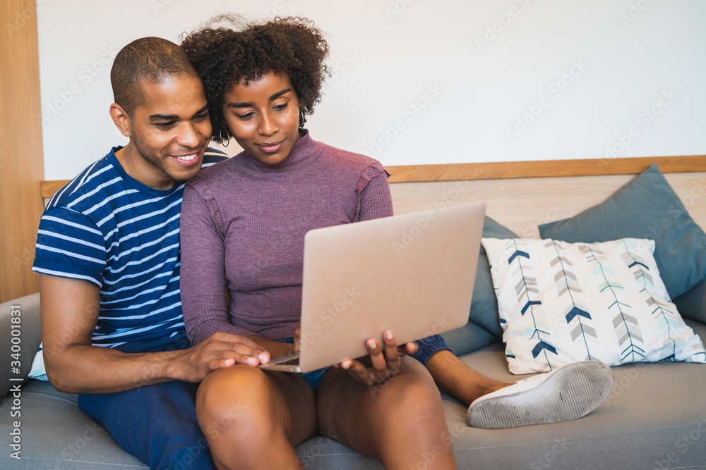 Fototapeta premium Young couple using laptop on couch at home.
