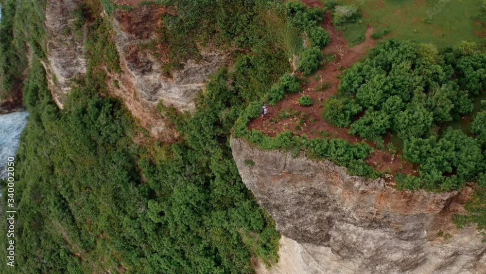 Aerial drone view of happy sporty plus size man traveler on a top of a mountain enjoying a sea view. Hiker at the rocky shore. Man on the hazard edge looks at the sea. Danger adventure lifestyle. Aerial drone view of happy sporty plus size man traveler on a top of a mountain enjoying a sea view. Hiker at the rocky shore. Man on the hazard edge looks at the sea. Danger adventure lifestyle.