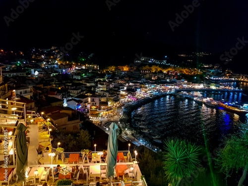 Aerial panoramic cityscape view of Parga city, Greece during the Summer. Beautiful architectural colorful buildings illuminated at night and night traffic near the port of Parga Epirus, Greece, Europe