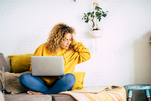 Adult blonde woman at home work with computer laptop and internet connection -concept of technology activity and smart job with modern people - lockdown quarantine for covid-19 photo