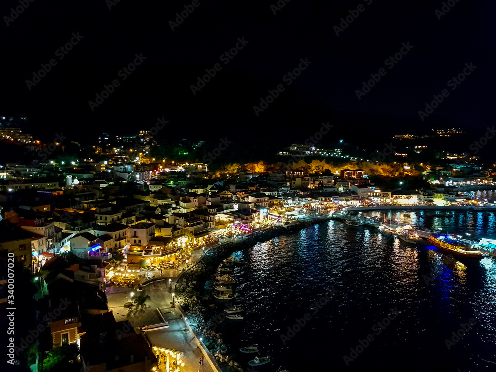 Aerial panoramic cityscape view of Parga city, Greece during the Summer. Beautiful architectural colorful buildings illuminated at night and night traffic near the port of Parga Epirus, Greece, Europe