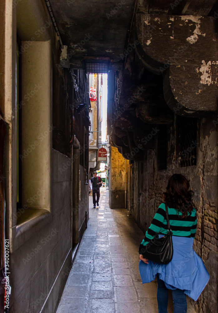 Tourists and residents walk around quiet streets in old town of Venice, Italy.