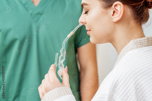 Woman receiving nasal inhalation in nose with essential oil in spa salon.