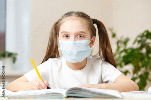 The child is studying at home, studying at home during quarantine, masked child studying at home