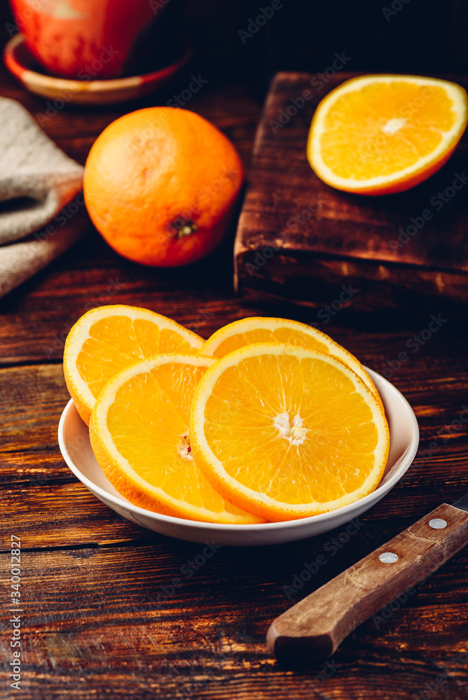 Slices of orange on white plate in rustic setting Slices of orange on white plate in rustic setting