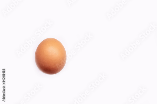 a single brown chicken egg is laid on a white background