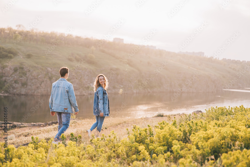 couple in love in blue jeans and white shirts in nature, where the field and rocks