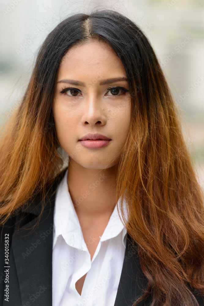 Young beautiful Asian businesswoman against view of the city Young beautiful Asian businesswoman against view of the city