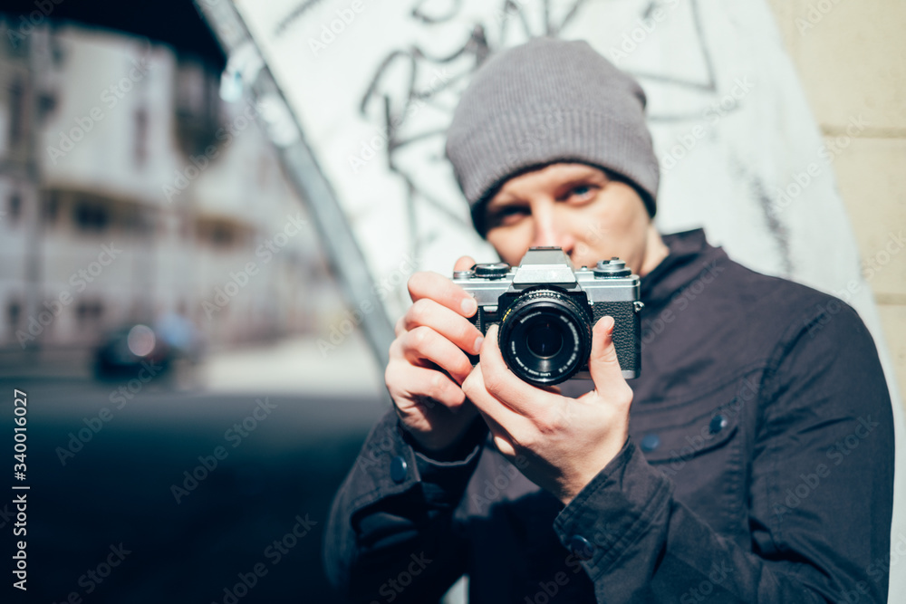 Closeup of young  man with digital camera outdoors. Young male photographer photographing nature