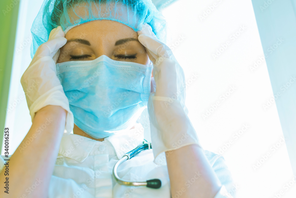 Fototapeta premium A woman doctor massages her temples because of a headache, bad health.