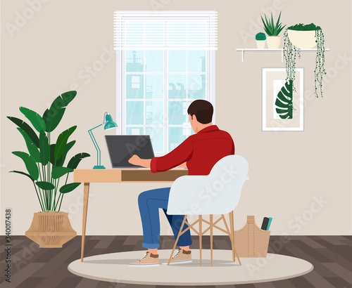 A freelancer man works behind a laptop. Home office workplace.