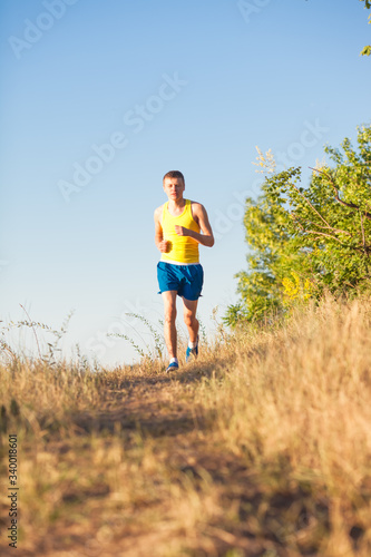 Young man running on a rural road during sunset