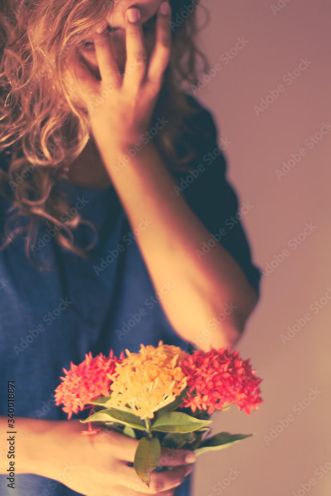 Woman in blue shirt holding a bouquet of orange and red flowers.