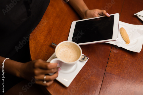 Black african american young yoman drinking coffee and using a tablet photo