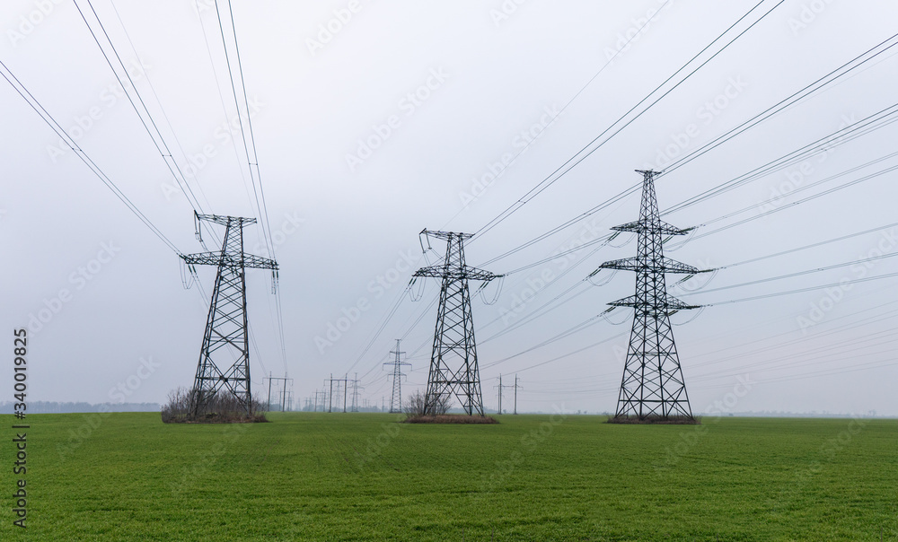 Electrical net of poles on a panorama of blue sky and green meadow Electrical net of poles on a panorama of blue sky and green meadow