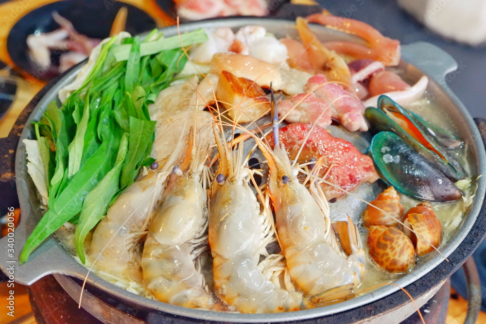 Sliced Pork and seafood on Thai Styled Coal Grill and Shabu Pan.Shrimp Clams in a Hot Pan.Close up.
