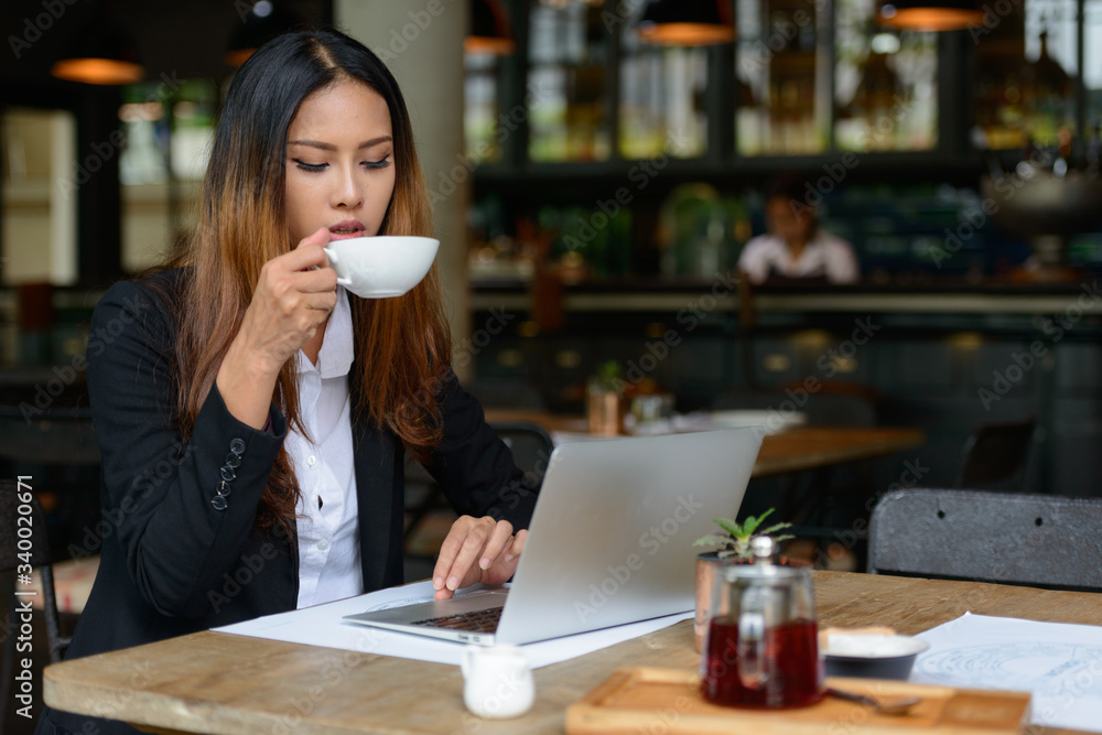 Young beautiful Asian businesswoman drinking coffee at the coffee shop Young beautiful Asian businesswoman drinking coffee at the coffee shop