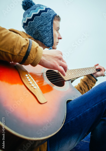 young man playing on guitar at the lake