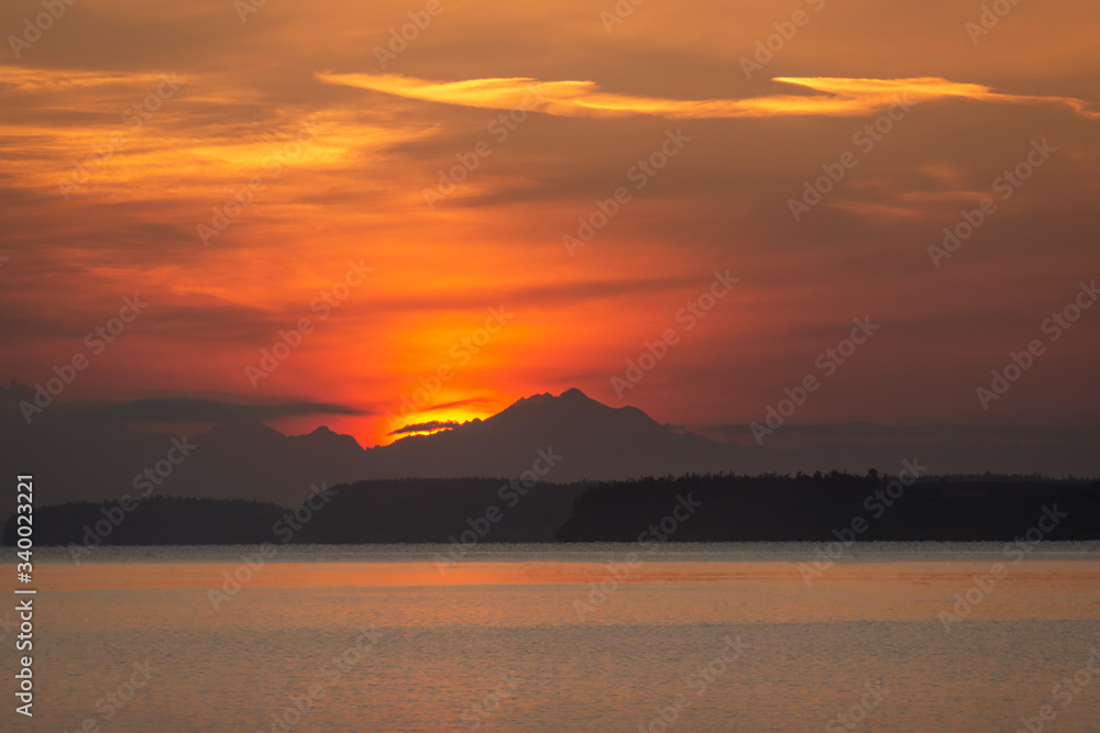 Brilliant orange sunrise over mountains and water