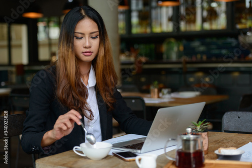 Young beautiful Asian businesswoman drinking coffee at the coffee shop