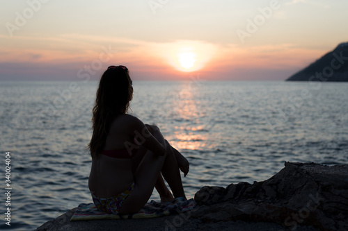 Silhouette of a young girl at the beaching watching the sunset © Kizaru