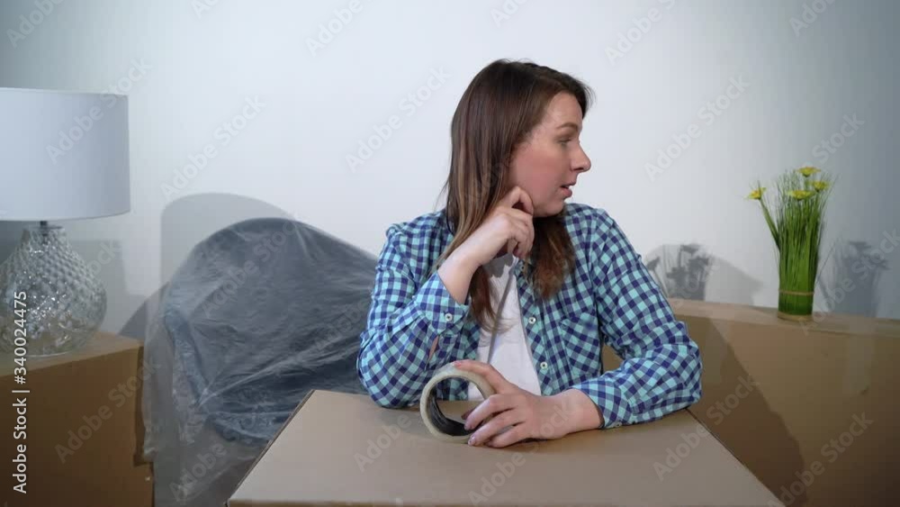 Moving into a new home. Woman apartment owner with box cardboard and tape tired and bored Moving into a new home. Woman apartment owner with box cardboard and tape tired and bored