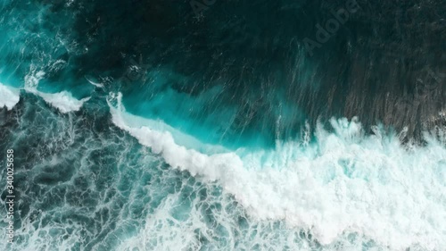 Timelapse. Aerial top view waves break on reef in a blue ocean. Sea waves on beautiful beach aerial view drone 4k shot. Bird's eye view of ocean waves crashing against an empty stone from above.