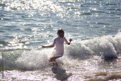 Little girl with shirt plays in the waves of the sea